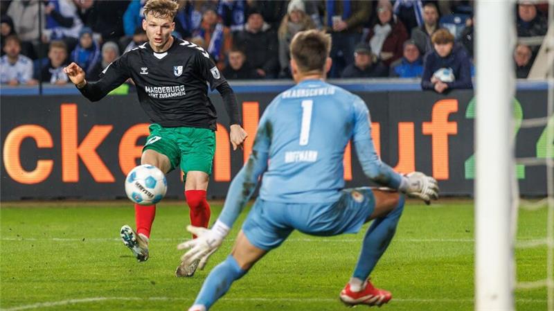 1. FC Magdeburg trotz Patzers Zweitliga-Spitzenreiter Magdeburgs Philipp Hercher (l) zieht ab gegen Torwart Ron-Thorben Hoffmann von Eintracht Braunschweig.