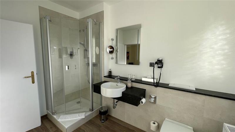 63 renovierte Zimmer – Hotel „Niedersächsischer Hof“ modernisiert Lichtdurchflutete Bäder und helle Fliesen nach der Renovierung.