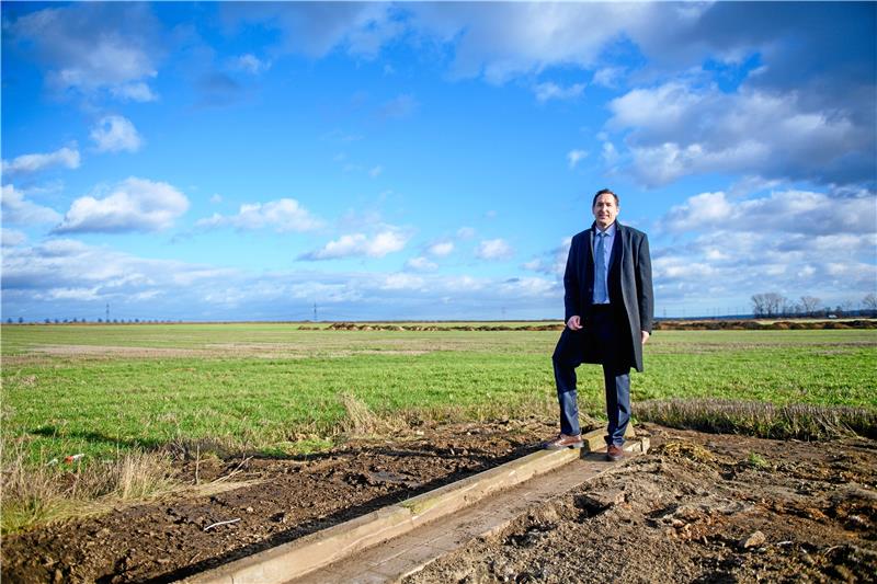 Mega-Summe: Daimler schafft 450 neue Jobs im Harz Uwe Kazmeier, Head of Customer Service and Parts Mercedes-Benz Trucks, steht am Rande einer brachliegenden Fläche. Dort will Daimler Truck ein zentrales Lager für Ersatzteile bauen. Foto: Gabbert/dpa